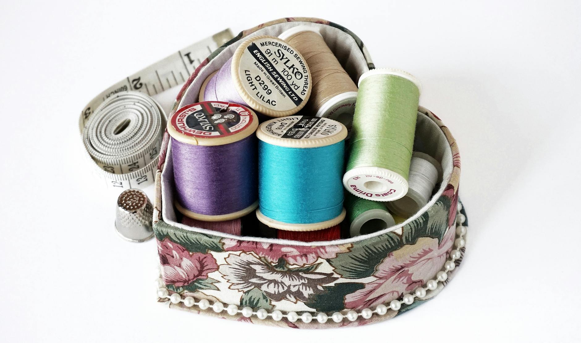 Kolorowe nici w pudełku z kwiatowym materiałem, akcesoria do szycia