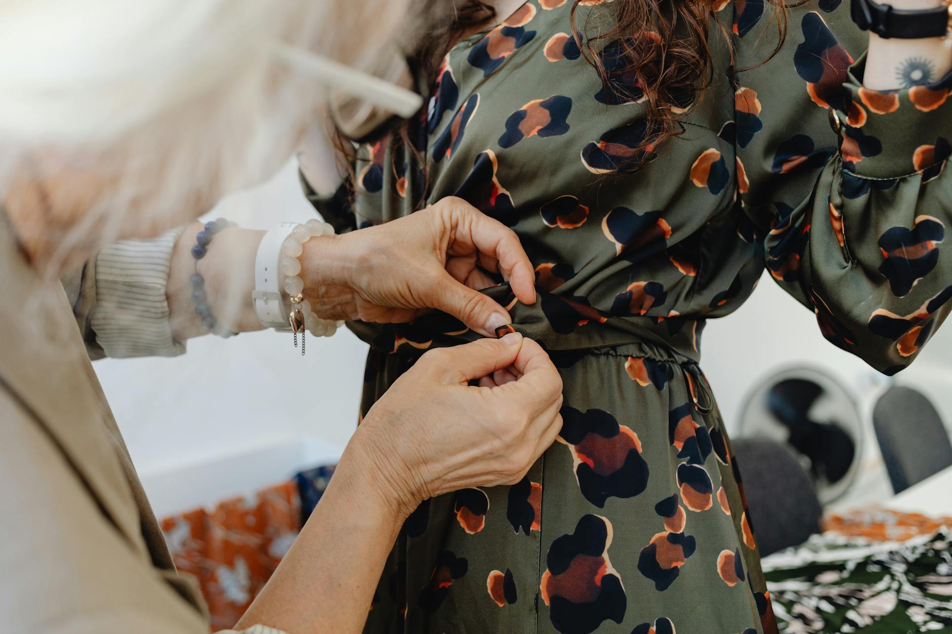 Krawcowa dopasowuje w talii wzorzystą sukienkę dziecięcą