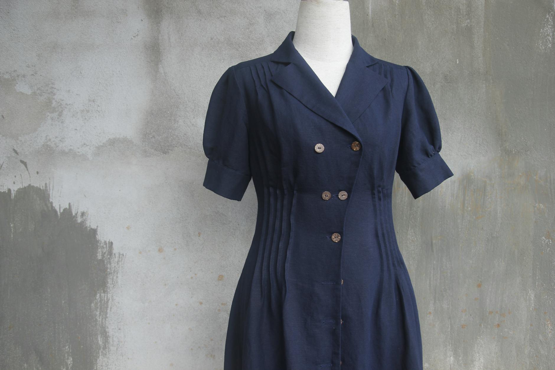 Niebieska sukienka z bufkami na manekinie na artystycznym tle