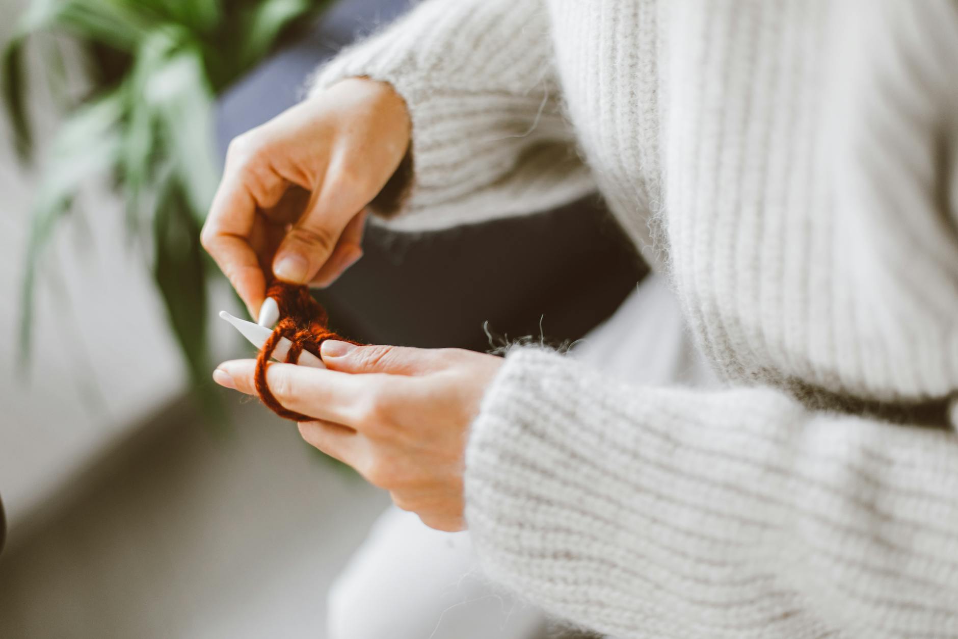 Dłonie robiące na drutach wełniany sweter z jasnej włóczki
