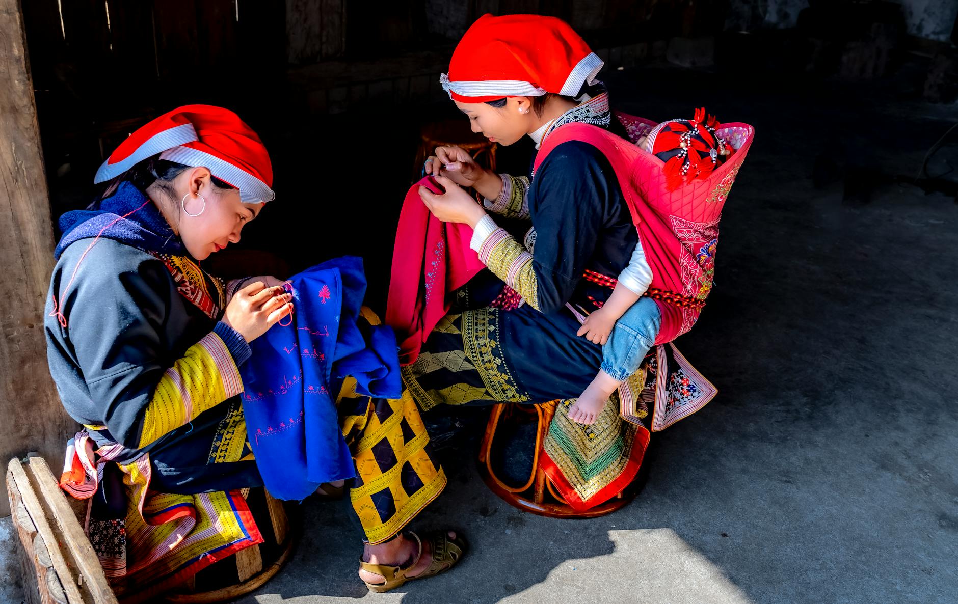 Kobiety szyją muślinową odzież dla dziecka w domowym wnętrzu