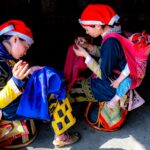 Kobiety w tradycyjnych strojach szyją spódnicę dla dziecka w domu