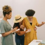 Trzy kobiety mierzą ubranie w pracowni krawieckiej