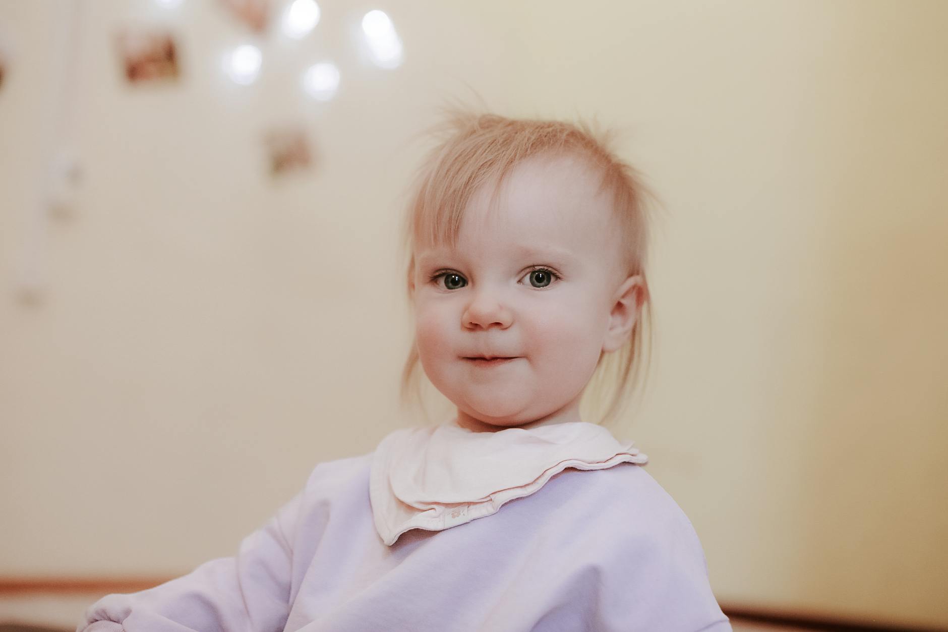 Uśmiechnięta blondwłosa dziewczynka w śliniaku bandana w domu